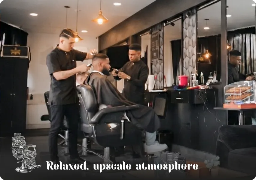 Interior view of the barbershop featuring leather chairs and barbers at work, showcasing a relaxing, elegant, and professional atmosphere.